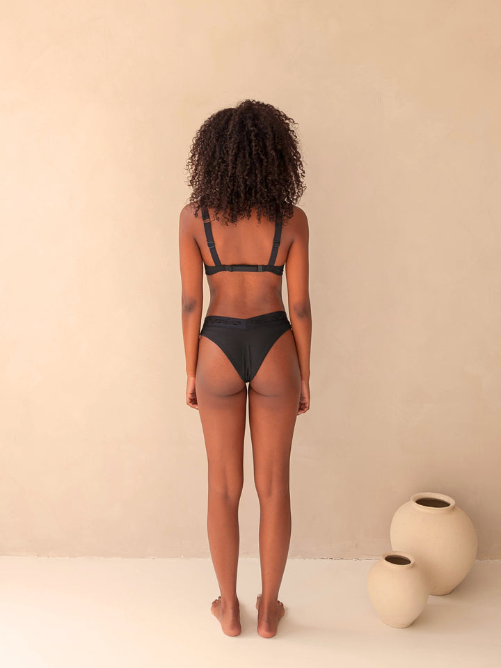 Bikini bottom V-shape in black, cheeky, with rib fabric and embroidery, woman back